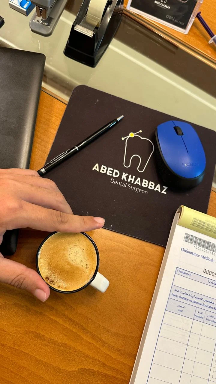 Dr. Abed Khabbaz branded desk accessories and a cup of coffee